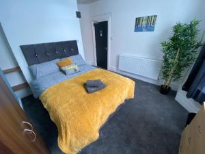 a bedroom with a bed with a yellow blanket at Bentley House with en-suites in Crewe