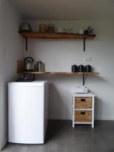 a kitchen with a white refrigerator and a shelf at Kaiteriteri Abel Tasman Inlet Views in Kaiteriteri