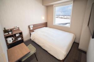 a small bedroom with a bed and a table and a window at Super Hotel Ishikari in Ishikari +37 photos