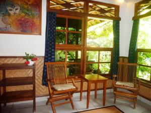 een kamer met stoelen, een tafel en ramen bij Saraswati Holiday House in Lovina