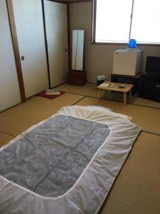 a large bed laying on the floor in a room at はらビジネス旅館 in Wakayama