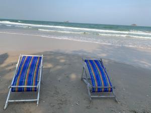2 sillas de playa sentadas en la arena de la playa en Mexican Beachfront Condo en Khao Tao