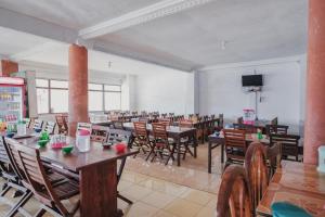una sala da pranzo con tavoli, sedie e TV di RedDoorz Syariah near Kebun Raya Liwa a Lampung