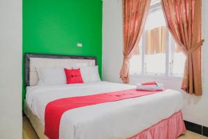 - une chambre avec un grand lit et un mur vert dans l'établissement RedDoorz Syariah near Kebun Raya Liwa, à Lampung