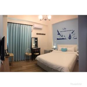 - une chambre avec un lit, un bureau et une télévision dans l'établissement Happy Wind Homestay, à Magong