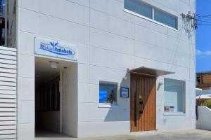 a white building with a door and a sign on it at Shima Stay holoholo in Zamami