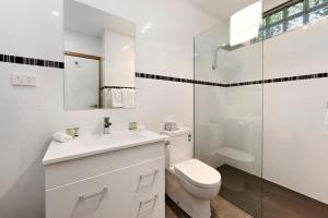 a white bathroom with a toilet and a shower at Commodore Regent in Launceston