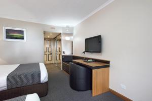 um quarto de hotel com uma cama e uma televisão de ecrã plano em Commodore Regent em Launceston