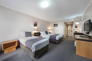 a hotel room with two beds and a flat screen tv at Commodore Regent in Launceston