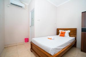 a bedroom with a bed with white sheets and orange pillows at KoolKost near RS Pelabuhan Jakarta - Minimum Stay 6 Nights in Jakarta