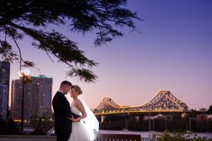 a bride and groom standing in front of a bridge at Stamford Plaza Brisbane in Brisbane