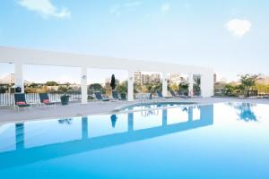 a swimming pool with chairs and a building in the background at Stamford Plaza Brisbane in Brisbane