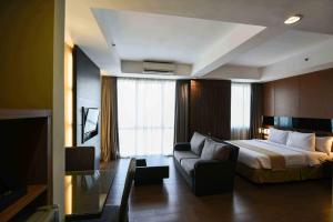 a hotel room with a bed and a couch at The Malibu Suites Balikpapan by Sissae Living in Balikpapan