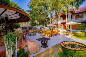 eine Terrasse mit Tischen und Stühlen und einem Teich mit Blumen in der Unterkunft E-outfitting Golden Country Hotel in Mandalay