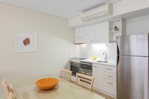 a kitchen with a stainless steel refrigerator and a table at Nesuto Geraldton in Geraldton