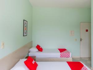 two beds in a room with red and white pillows at OYO Hotel Cosmópolis, Sao Paulo in Cosmópolis