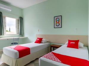 two beds in a room with red and white at OYO Hotel Cosmópolis, Sao Paulo in Cosmópolis