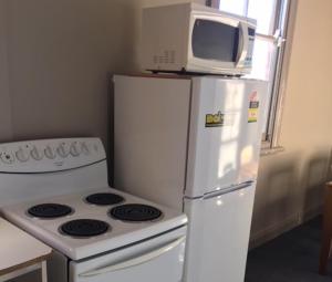 a microwave on top of a refrigerator next to a stove at Commercial Hotel Motel Lithgow in Lithgow