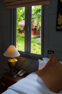 a bedroom with a bed with a lamp and a window at Ma Doo Bua Phuket - SHA Extra Plus in Thalang