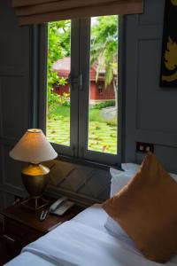 um quarto com uma cama com um candeeiro e uma janela em Ma Doo Bua Phuket - SHA Extra Plus em Thalang