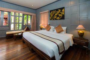 een slaapkamer met een groot bed en een bank bij Ma Doo Bua Phuket - SHA Extra Plus in Thalang