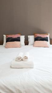 two rolled up towels on a white bed with pillows at Prinya house ปริญญา เฮ้าส์ in Ban Huai Kapi