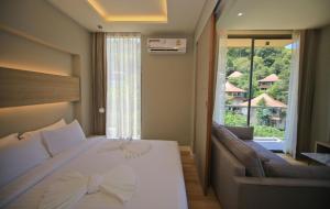 a bedroom with a bed and a couch and a window at Rocco Aonang Krabi in Ao Nang Beach