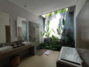 een badkamer met een wastafel en een grote plant bij Santun Luxury Private Villas-CHSE CERTIFIED in Ubud