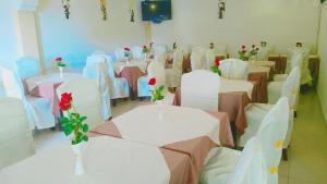 ein Raum mit Tischen und Stühlen mit Rosen in Vasen in der Unterkunft Winta Hotel in Hārer