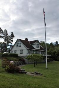 a white house with a flag pole in the yard at Huset i skogen in Moss