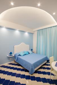 a bedroom with a blue and white bed and blue curtains at Marilisa Holidays in Maiori