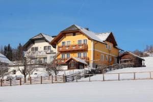 ein großes Gebäude im Schnee mit einem Zaun in der Unterkunft Haus Holzer in Sankt Andrä im Lungau