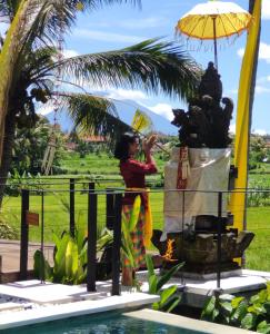 een vrouw die naast een fontein staat met een paraplu bij Santun Luxury Private Villas-CHSE CERTIFIED in Ubud