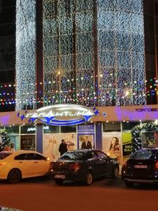 two cars parked in front of a building with christmas lights at Smart Apartment на Соборной 23 in Kremenchuk