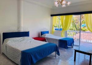 1 dormitorio con 2 camas y una ventana con cortinas amarillas en SweetWater Resort, en Zamboanguita