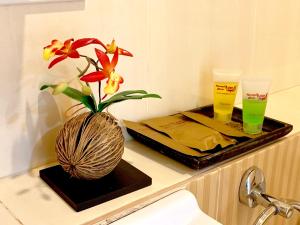 a flower in a vase on a counter with two drinks at Kannapat House in Ban Nong Thale