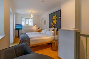 una camera con letto king-size e divano di ANA Living Augsburg City Center by Arthotel ANA - Self-Service-Hotel a Augusta (Augsburg)