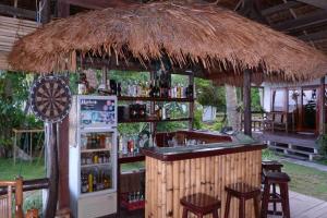 un bar en una cabaña de paja con nevera y taburetes en Romantic Beach Villas en General Luna