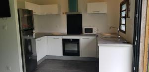 a small kitchen with white cabinets and a sink at Au chant du coq in Salazie