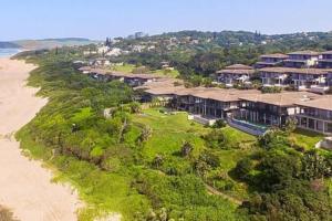 a group of houses on a hill next to the beach at Whale Watchers Paradise - 7 Sovereign Sands in KwaDukuza