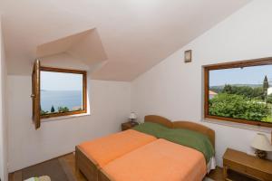 1 Schlafzimmer mit einem orangenen Bett und 2 Fenstern in der Unterkunft Apartments Kisic in Mlini