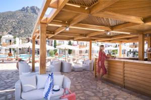 a woman standing at a bar at a resort at Mitsis Selection Blue Domes in Kardamaina
