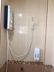 a shower in a bathroom with a soap dispenser on a wall at Burapha Bangsaen Garden Apartment in Bangsaen