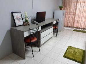 a desk with a television and two chairs in a room at Burapha Bangsaen Garden Apartment in Bangsaen