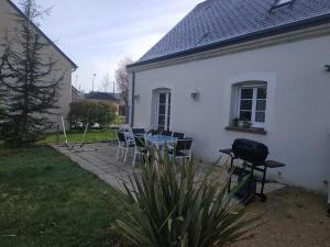 een wit huis met een tafel en stoelen in de tuin bij CHEZ MARLYSE in Blois