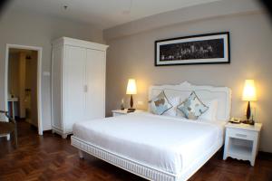a bedroom with a large white bed with two lamps at Colmar Tropicale in Bukit Tinggi