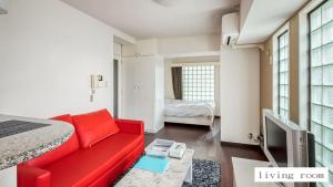 Una sala de estar con un sofá rojo y un televisor. en Aparthotel Status59, en Sapporo