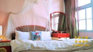 1 dormitorio con 1 cama con espejo grande en Ponkan Inn, en Beigang