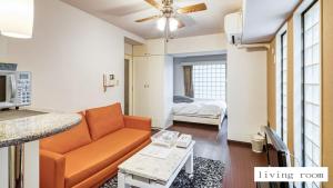 sala de estar con sofá naranja y cama en Aparthotel Status59 with Parking en Sapporo