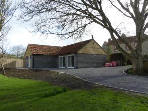 uma casa de tijolos com uma árvore e uma entrada em The Woodshed - A newly built, 2 bedroom, cottage near Glastonbury em Glastonbury